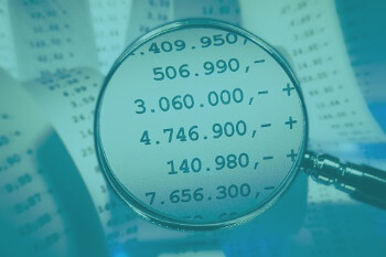 Eine Lupe vergrößert einige Beträge von einem Kassenzettel für die Wirtschaftsprüfung