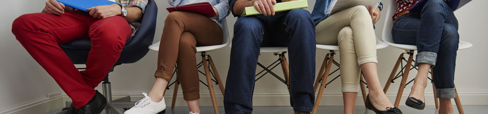 Bewerber sitzen in einer Reihe mit überschlagenen Beinen