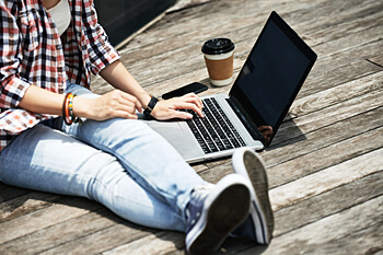 Studentin sitzt mit Kaffee und Laptopo