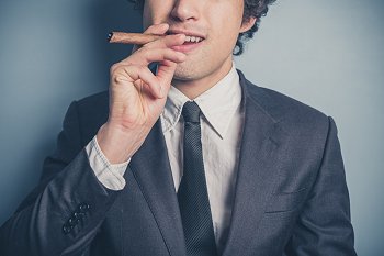 Dualer Student im Anzug raucht Zigarre