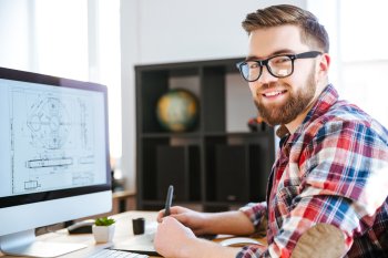 Student sitzt an Computer und lächelt in Kamera
