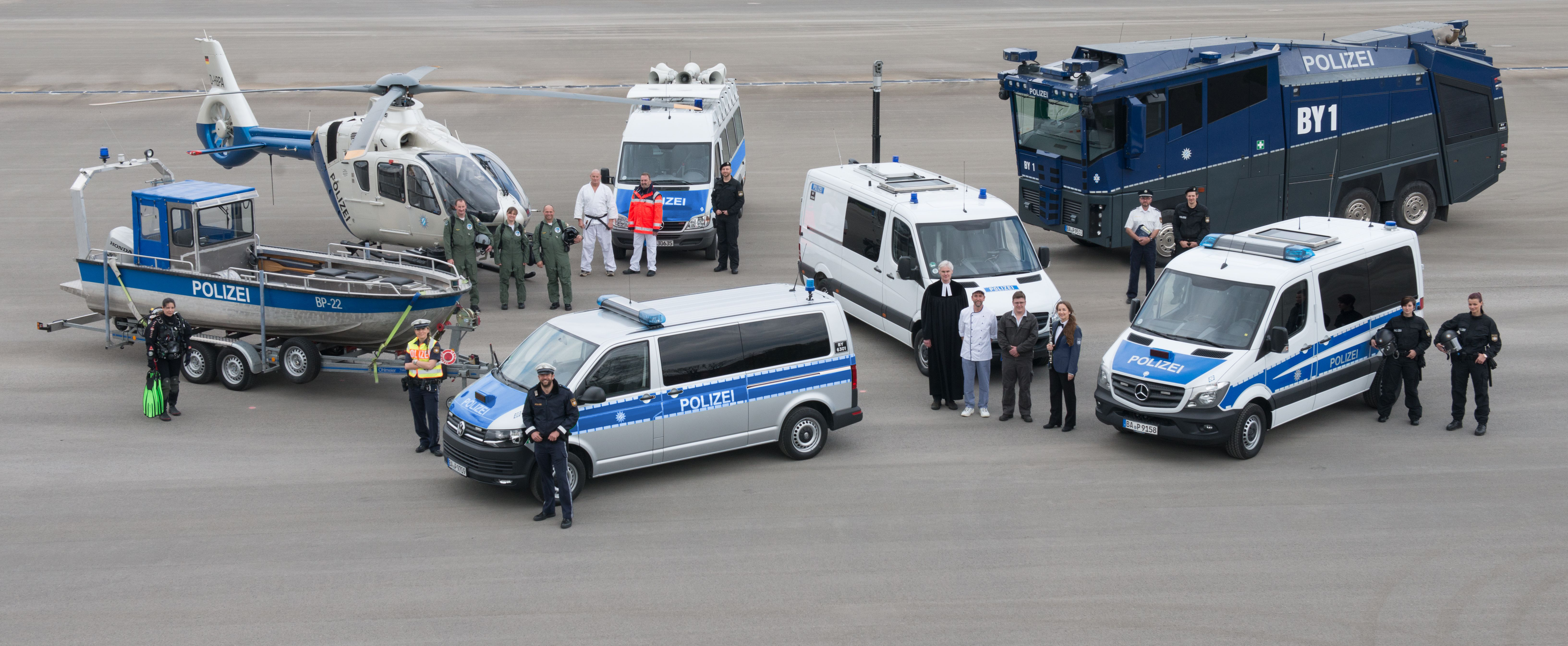 Mitabeiterinnen und Mitarbeiter der Polizei vor verschiedenen Dienstfahrzeugen